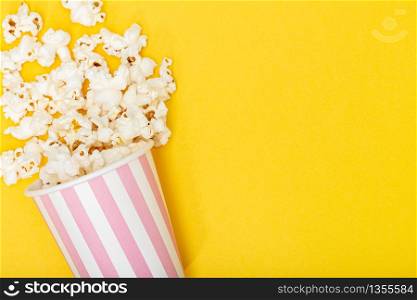 Popcorn bucket on yellow background. Movie or TV background. Top view Copy space