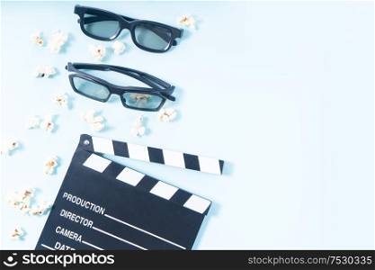 popcorn, cinema clapper and two pairs of 3d glasses over plain blue background, movie and cinema concept. popcorn and 3d glasses