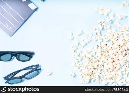 popcorn, cinema clapper and two pairs of 3d glasses over plain blue background, movie and cinema concept, top view frame. popcorn and 3d glasses