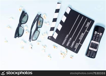 popcorn, cinema clapper, remote control for TV and two pairs of 3d glasses over blue background, movie and cinema concept. popcorn and 3d glasses