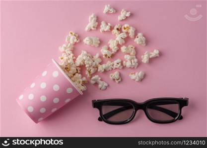 Popcorn, cup and 3d glasses on a pastel pink background.
