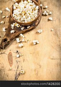 Popcorn in a wooden bowl on the Board. On a wooden table.. Popcorn in a wooden bowl on the Board.