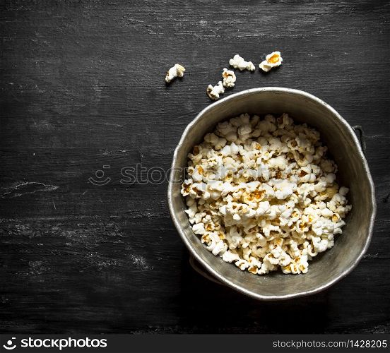 Popcorn in an old pot. On the black wooden table.. Popcorn in an old pot.