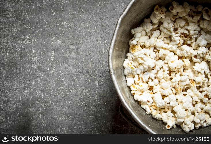 Popcorn in an old pot. On the Stone table.. Popcorn in an old pot.