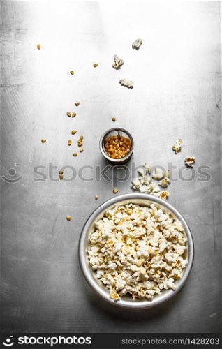 Popcorn in bowl with corn. On the metal table.. Popcorn in bowl with corn.
