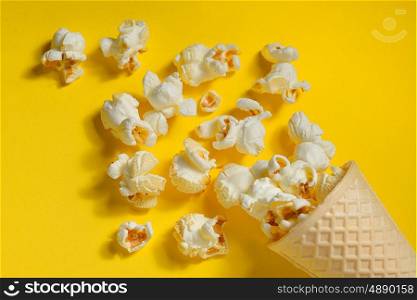 Popcorn in ice cream cones on yellow background