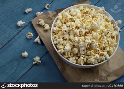 Popcorns kept in a bowl on a blue wooden table. 