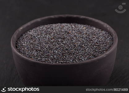 poppy seeds in a stone bowl on a dark background