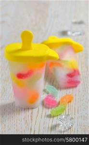 popsicles ice pops with gummy candy on wooden background