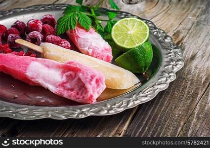 Popsicles served with raspberries and lime on a metal tray.Selective focus. raspberry ice cream with old tray