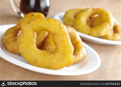 Popular Peruvian dessert called Picarones made from squash and sweet potato and served with Chancaca syrup (kind of honey), which can be seen in the back, on plastic plate (Selective Focus, Focus on the front). Peruvian Dessert Called Picarones