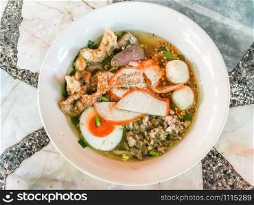 Popular Thai food and street food concept from Noodle Tom Yam, noodles with pork and hot spicy soup for lunch or dinner on wooden floor, Top view.