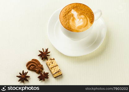 porcelain cup of cappucino, sweet and spices on white background