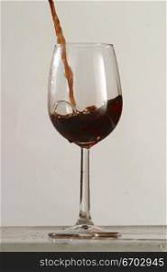 Poring red wine into a glass.Stop motion photography. By use of a sound activated switch, I am able to capture the moment that a glass breaks. Pictured here a glass of red wine.