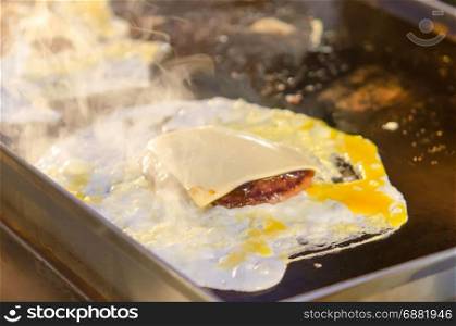 Pork and eggs with cheese on a pan.