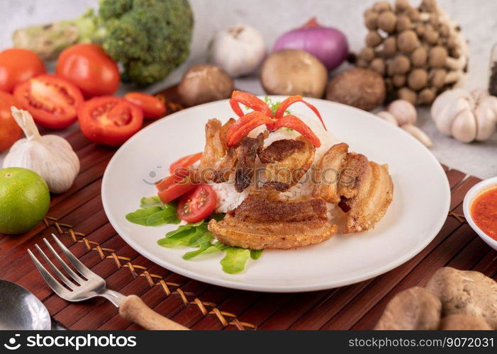 Pork belly fried on steamed rice on a plate. Selective focus.