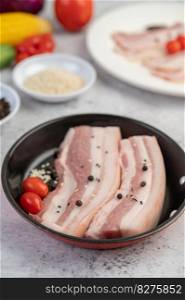 Pork belly in a pan with pepper seeds Tomatoes and spices. Selective focus.