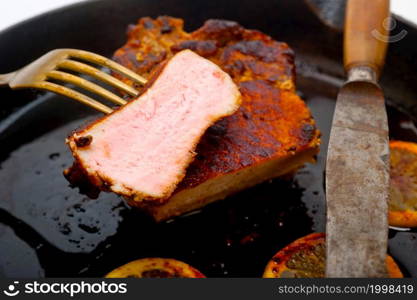 pork chop seared on iron skillet with lemon and spices seasoning