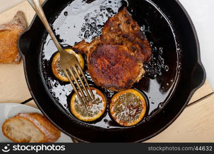 pork chop seared on iron skillet with lemon and spices seasoning