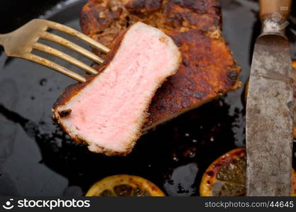 pork chop seared on iron skillet with lemon and spices seasoning