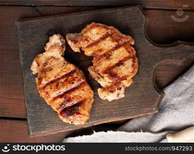 pork fried steak lies on a vintage brown wooden board, top view