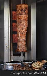 Pork gyros on vertical broiler rotisserie machine and grilled pita souvlaki bread. Traditional greek fast food.