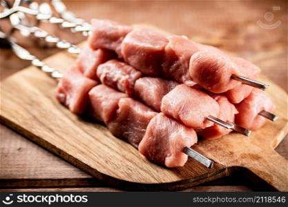Pork kebab raw on a cutting board. On a wooden background. High quality photo. Pork kebab raw on a cutting board.