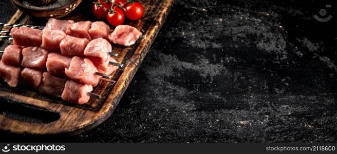 Pork kebab raw on a wooden cutting board. On a black background. High quality photo. Pork kebab raw on a wooden cutting board.