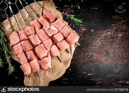 Pork kebab raw on paper. On a rustic dark background. High quality photo. Pork kebab raw on paper.