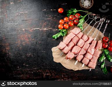 Pork kebab raw with parsley and cherry tomatoes. Against a dark background. High quality photo. Pork kebab raw with parsley and cherry tomatoes.