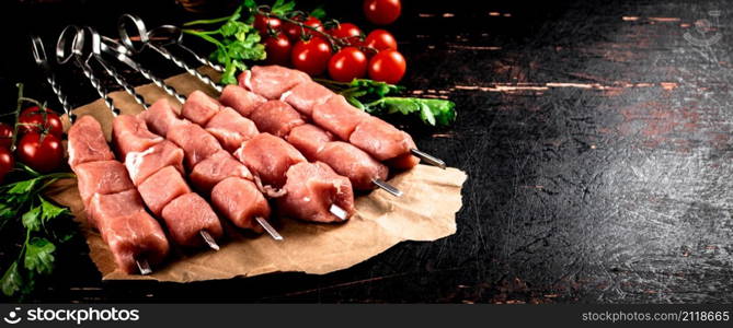 Pork kebab raw with parsley and cherry tomatoes. Against a dark background. High quality photo. Pork kebab raw with parsley and cherry tomatoes.