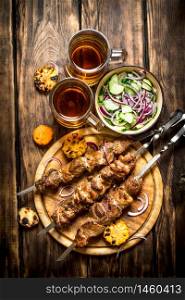 Pork kebab with beer and vegetables. On wooden background.. Pork kebab with beer and vegetables.