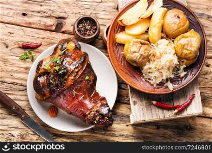 Pork knuckle on rustic table.Roasted pork knuckle with potatoes. Pork knuckle with fried sauerkraut