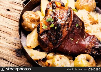 Pork knuckle on wooden surface.Roasted pork knuckle with potatoes. Pork knuckle with fried sauerkraut
