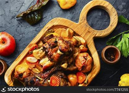 Pork knuckle or shank grilled with apples on cutting board. Roasted meat with autumn fruits