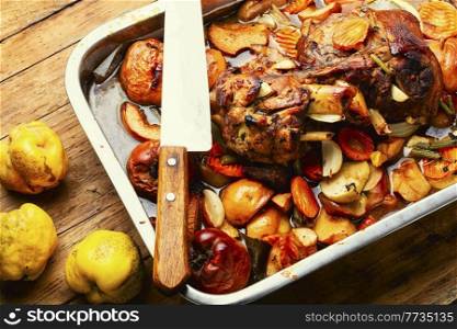 Pork knuckle stewed with quince and apples in tray. Pork leg baked with apples