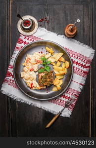 Pork loin steaks with herbs crust, roast potatoes and salsa sauce in rustic plate , top view