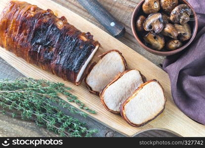 Pork loin wrapped in bacon with roasted mushrooms