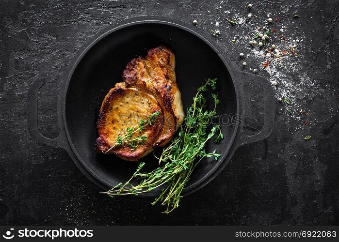 Pork meat, grilled steak on black background, top view