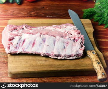 Pork meat on a cutting board, near a kitchen knife