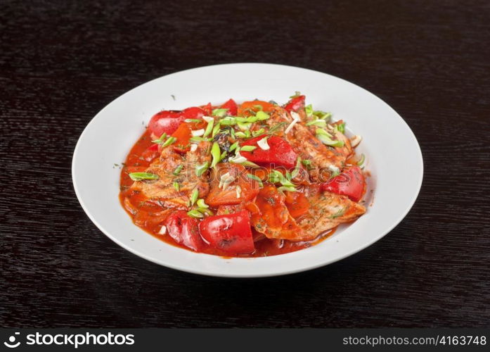 pork meat with tomato, pepper, prunes, garlic and green onion