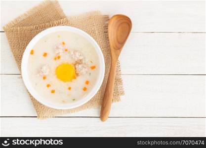 Pork porridge put eggs in a cup on a white wooden floor,Top view and copy space