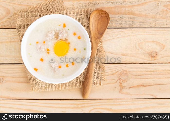 Pork porridge put eggs in a cup on brown wooden floor,Top view and copy space
