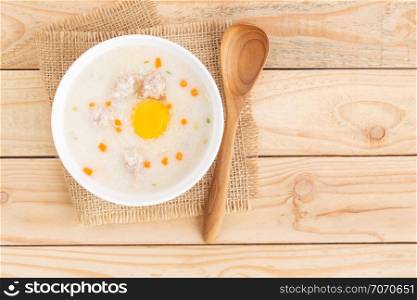 Pork porridge put eggs in a cup on brown wooden floor,Top view and copy space