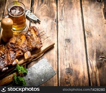 Pork ribs grilled with a meat hatchet and beer. On a wooden table.. Pork ribs grilled with a meat hatchet and beer.