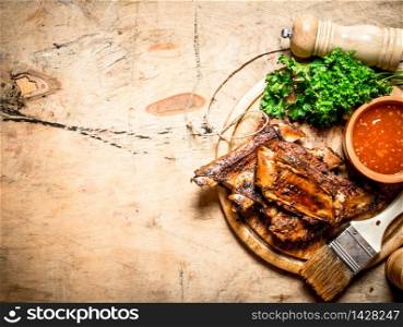 Pork ribs grilled with a spicy sauce and a brush. On wooden background.. Pork ribs grilled