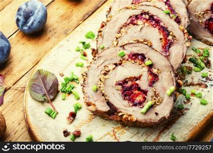 Pork roll baked with autumn plum and nuts. Delicious meat roll with plum