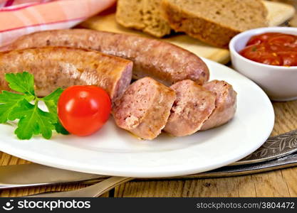 Pork sausages fried in a dish, bread, sauce, tomato, parsley, fork, knife, napkin on the background of wooden boards