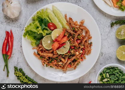 Pork Skin Larb with carrot, cucumber, lime, spring onion, chili, freshly ground pepper, and lettuce.