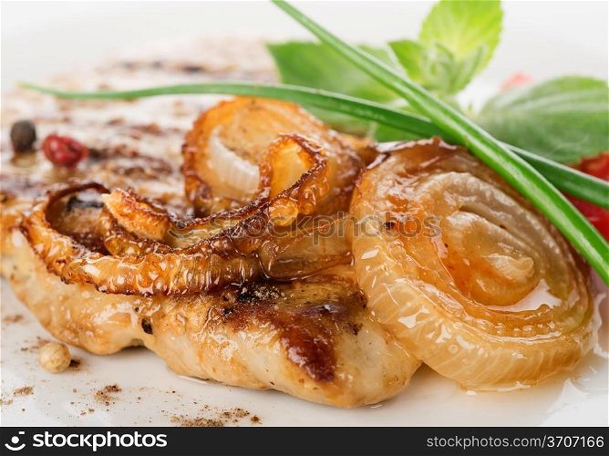 Pork steak with fried onion on a white plate close-up